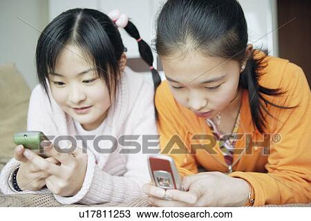 Close-up of two sisters using mobile phones View Large Photo Image Stock Image - Close-up of two sisters using mobile phones. Fotosearch