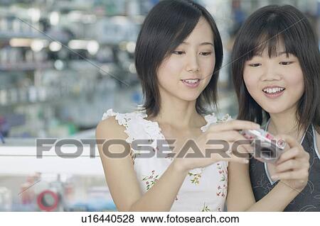 Stock Photo - Close-up of two young women holding a camera. Fotosearch