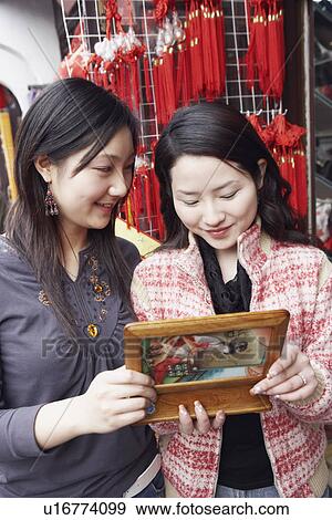 Stock Photo - Close-up of two young women looking at a jewelry box smiling. Fotosearch