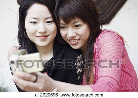 Close-up of two young women taking a photograph of themselves View Large Photo Image Stock Photograph - Close-up of two young women taking a photograph of themselves. Fotosearch
