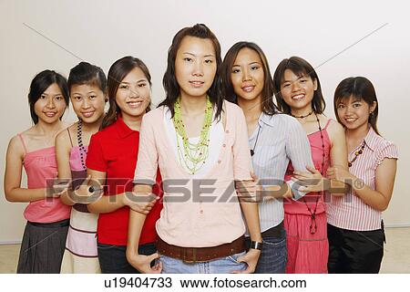 Stock Image - Portrait of a group of young women holding hands of each other and smiling. Fotosearch