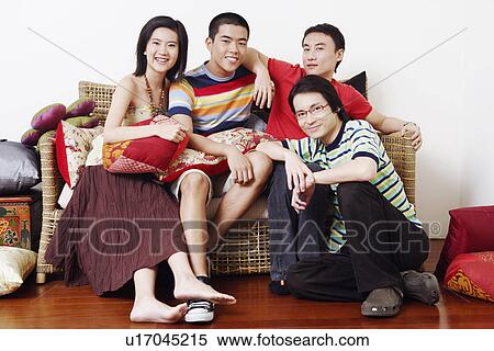 Portrait of a young couple and two mid adult men sitting on a couch and smiling View Large Photo Image Stock Photography - Portrait of a young couple and two mid adult men sitting on a couch and smiling. Fotosearch