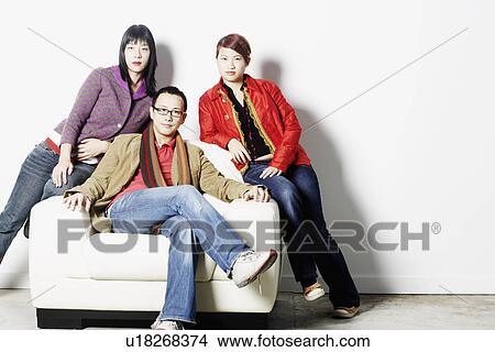 Picture - Portrait of a young man sitting with two young women. Fotosearch