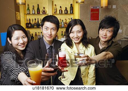 Stock Image - Portrait of four friends holding drinks. Fotosearch