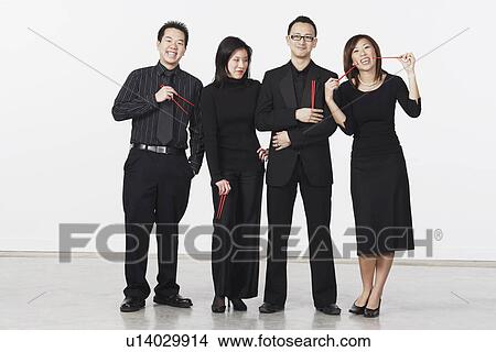 Portrait of two young men and two young women standing and holding chopsticks View Large Photo Image Picture - Portrait of two young men and two young women standing and holding chopsticks. Fotosearch