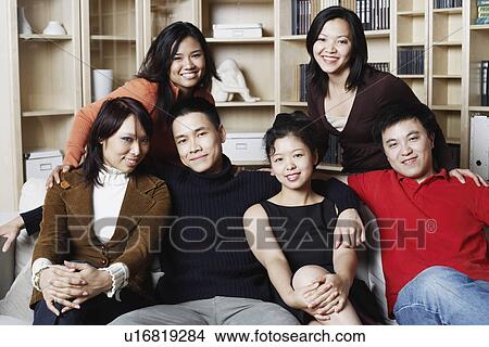 Picture - Portrait of two young men sitting together on a couch with four young women smiling. Fotosearch