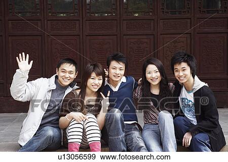 Stock Photo - Portrait of two young women and three young men sitting together. Fotosearch