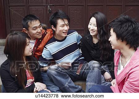 Stock Photo - Two young men talking to two young women and a teenage boy. Fotosearch
