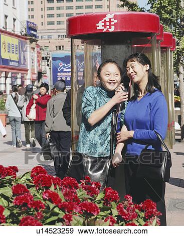 Two young women talking on a pay phone View Large Photo Image Stock Photo - Two young women talking on a pay phone. Fotosearch