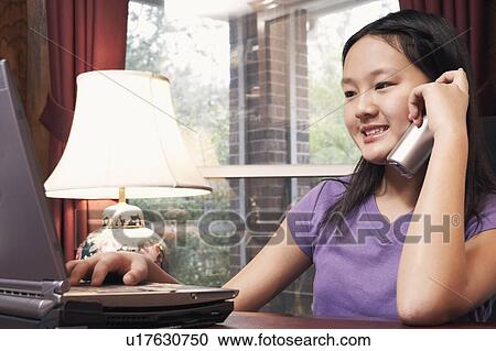 Stock Image - Close-up of a girl talking on a cordless telephone. Fotosearch