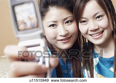 Stock Photo - Close-up of a teenage girl and a young woman taking a photograph of themselves. Fotosearch