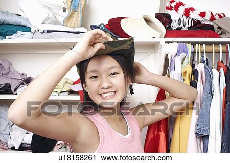 Stock Image - Portrait of a girl holding a hat on her head. Fotosearch