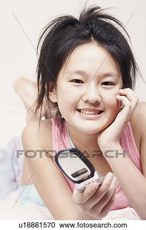 Stock Image - Portrait of a girl holding a mobile phone. Fotosearch