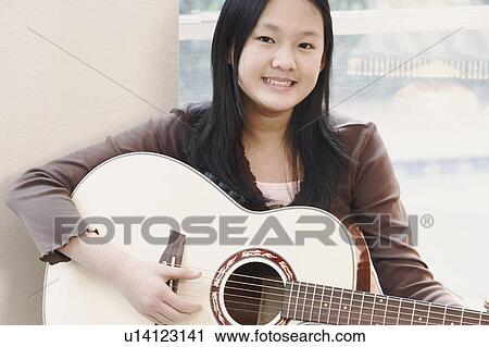 Stock Image - Portrait of a girl playing the guitar. Fotosearch