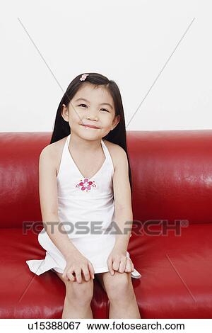 Stock Photo - Portrait of a girl sitting on a couch. Fotosearch