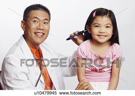 Stock Photography - Portrait of a male doctor examining his patient. Fotosearch