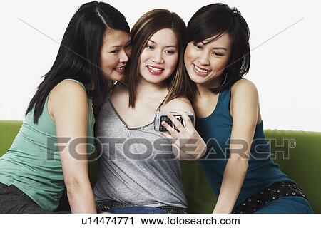 Close-up of three young women taking a photograph of themselves with a mobile phone camera View Large Photo Image Stock Image - Close-up of three young women taking a photograph of themselves with a mobile phone camera. Fotosearch