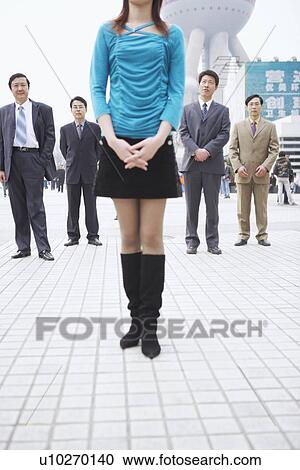 Four businessmen standing behind a young woman View Large Photo Image Stock Image - Four businessmen standing behind a young woman. Fotosearch
