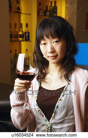 Portrait of a young woman holding a glass of red wine View Large Photo Image Picture - Portrait of a young woman holding a glass of red wine. Fotosearch