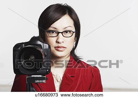 Stock Image - Portrait of a young woman holding a camera. Fotosearch
