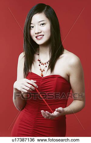Stock Photograph - Portrait of a young woman holding chopsticks. Fotosearch