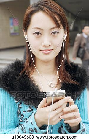 Portrait of a young woman listening to an MP3 player View Large Photo Image Stock Image - Portrait of a young woman listening to an MP3 player. Fotosearch