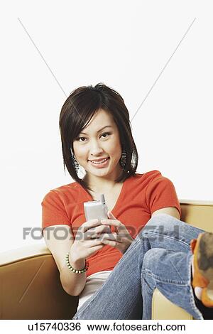 Portrait of a young woman operating a mobile phone View Large Photo Image Stock Photograph - Portrait of a young woman operating a mobile phone. Fotosearch