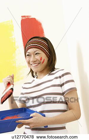 Stock Photo - Close-up of a young woman holding a paint tray and a paintbrush. Fotosearch