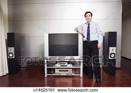 Portrait of a businessman standing by the side of a television View Large Photo Image Stock Image - Portrait of a businessman standing by the side of a television. Fotosearch