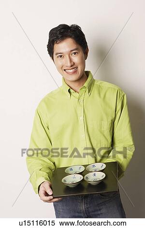 Portrait of a young man holding a tray of bowls smiling View Large Photo Image Stock Photography - Portrait of a young man holding a tray of bowls smiling. Fotosearch