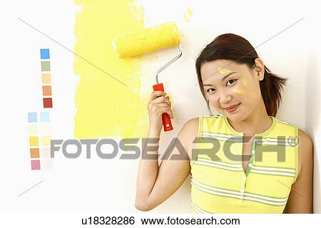 Portrait of a young woman holding a paint roller View Large Photo Image Stock Photograph - Portrait of a young woman holding a paint roller. Fotosearch