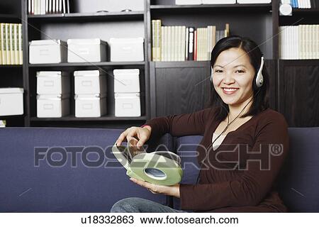 Stock Image - Portrait of a young woman listening to music on headphones. Fotosearch