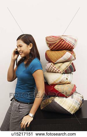 Stock Image - Side profile of a young woman talking on a mobile phone and smiling. Fotosearch