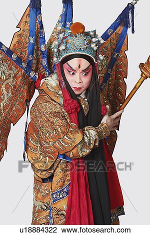 Stock Image - Close-up of a male Chinese opera performer holding a weapon. Fotosearch
