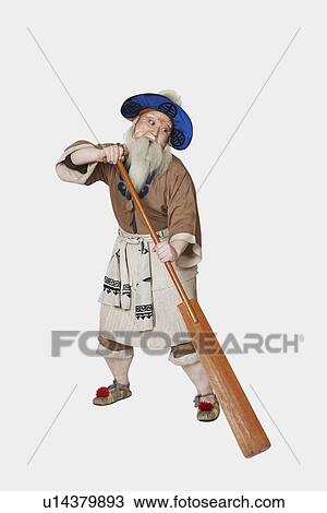 Stock Image - Mid adult man standing holding an oar. Fotosearch
