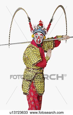 Stock Image - Side profile of a male Chinese opera performer gesturing with a weapon. Fotosearch