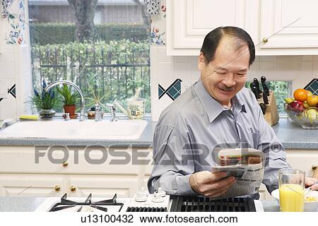 Close-up of a senior man reading a newspaper in the kitchen View Large Photo Image Stock Image - Close-up of a senior man reading a newspaper in the kitchen. Fotosearch