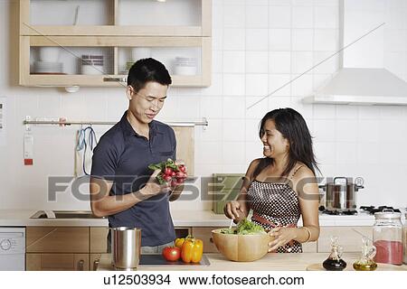 Picture - Close-up of a young man and a young woman standing and holding root vegetables. Fotosearch