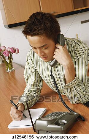 Close-up of a young man using a telephone in the kitchen View Large Photo Image Stock Photograph - Close-up of a young man using a telephone in the kitchen. Fotosearch