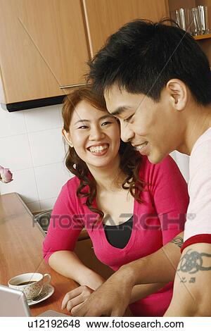 Close-up of a young woman and a mid adult man smiling at a kitchen counter View Large Photo Image Stock Photo - Close-up of a young woman and a mid adult man smiling at a kitchen counter. Fotosearch