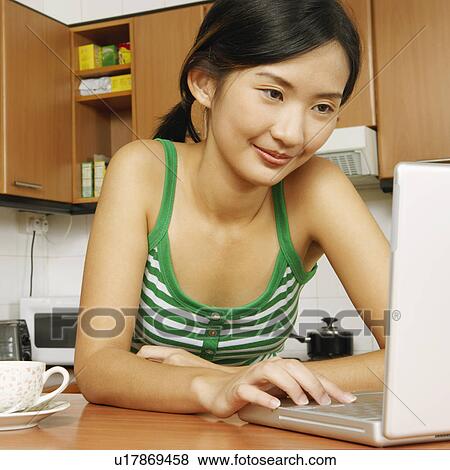 Close-up of a young woman using a laptop at a kitchen counter View Large Photo Image Stock Photo - Close-up of a young woman using a laptop at a kitchen counter. Fotosearch