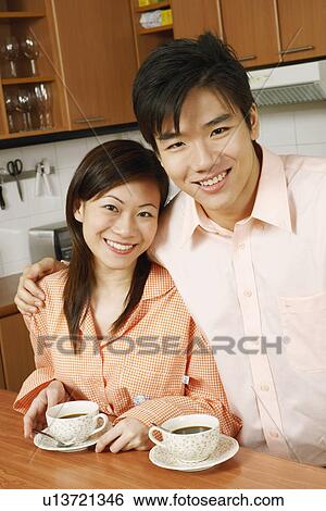 Stock Photograph - Portrait of a young couple smiling at a kitchen counter. Fotosearch