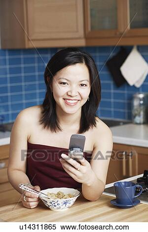 Stock Photography - Portrait of a young woman holding a mobile phone smiling. Fotosearch