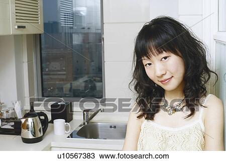 Portrait of a young woman standing in the kitchen smiling View Large Photo Image Stock Image - Portrait of a young woman standing in the kitchen smiling. Fotosearch