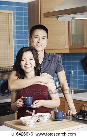 Stock Photograph - Portrait of a young woman standing with a young man holding a tea cup. Fotosearch