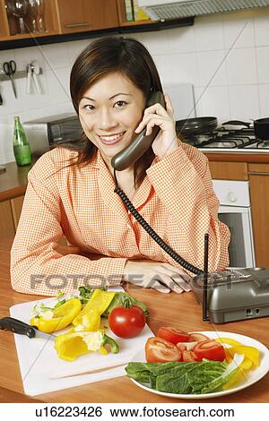 Portrait of a young woman using a telephone in the kitchen View Large Photo Image Stock Photograph - Portrait of a young woman using a telephone in the kitchen. Fotosearch