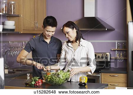 Young man helping a young woman prepare food View Large Photo Image Stock Photo - Young man helping a young woman prepare food. Fotosearch
