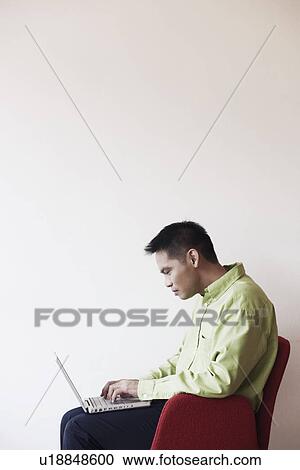 Businessman sitting in an armchair and using a laptop View Large Photo Image Stock Image - Businessman sitting in an armchair and using a laptop. Fotosearch
