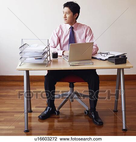 Stock Image - Businessman sitting in an office and thinking. Fotosearch