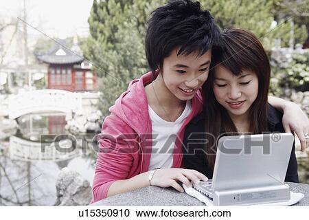 Stock Image - Close-up of a teenage boy and a young woman using a laptop. Fotosearch